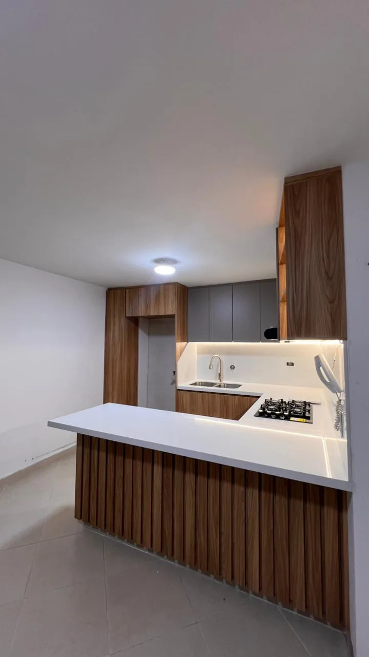 Barra de la cocina revestida en listones verticales de madera con encimera de cuarzo blanco