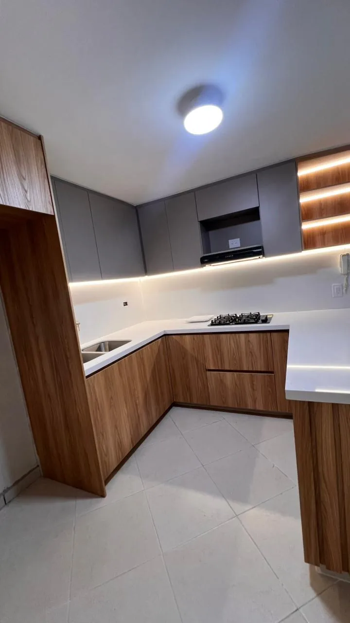 Esquina de la cocina con cooktop, lavaplatos y torre de despensa en laminado macadamia