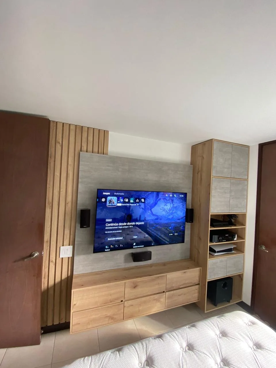 Mueble de televisión construido con panel gris, listones de madera, cajones flotantes y torre lateral con nichos