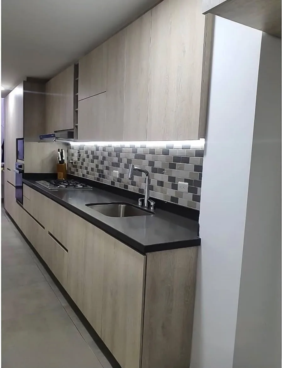 Mesón de la cocina con luz LED bajo alacena y salpicadero en mosaico gris