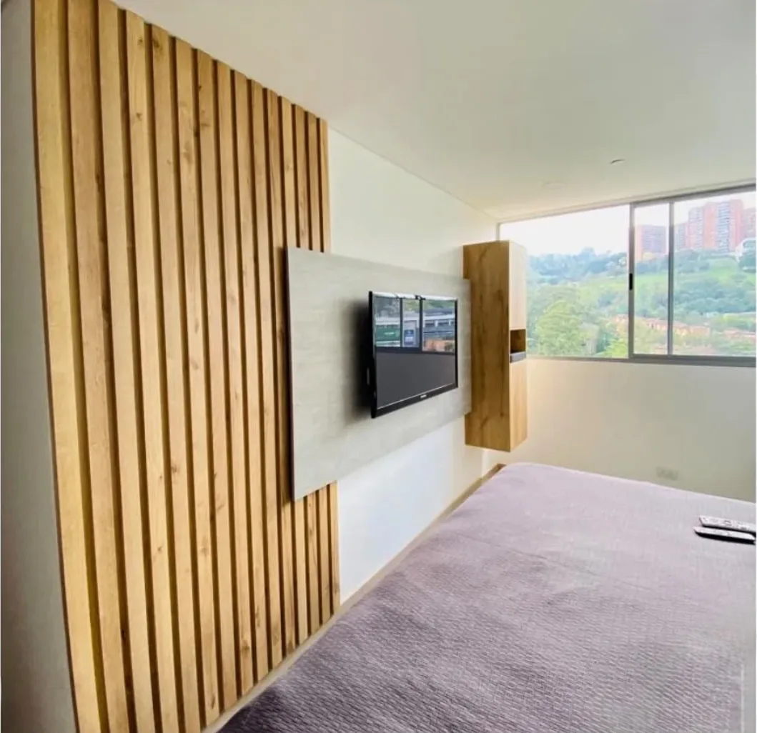 Segundo mueble de televisión: pared de listones de madera y panel gris flotante frente a un ventanal con vista a la ciudad